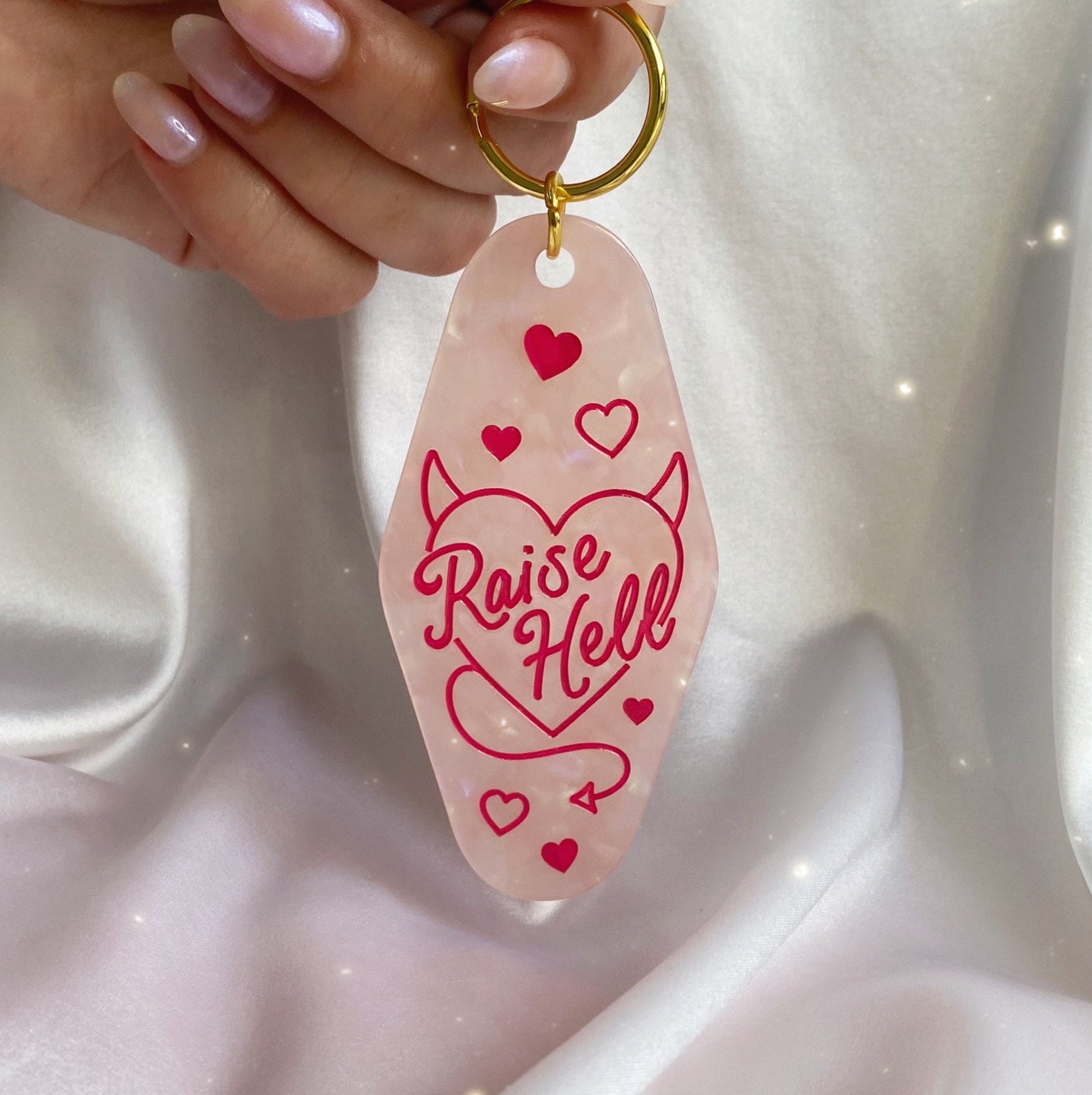 raise hell motel keychain - pink opalescent - in hand